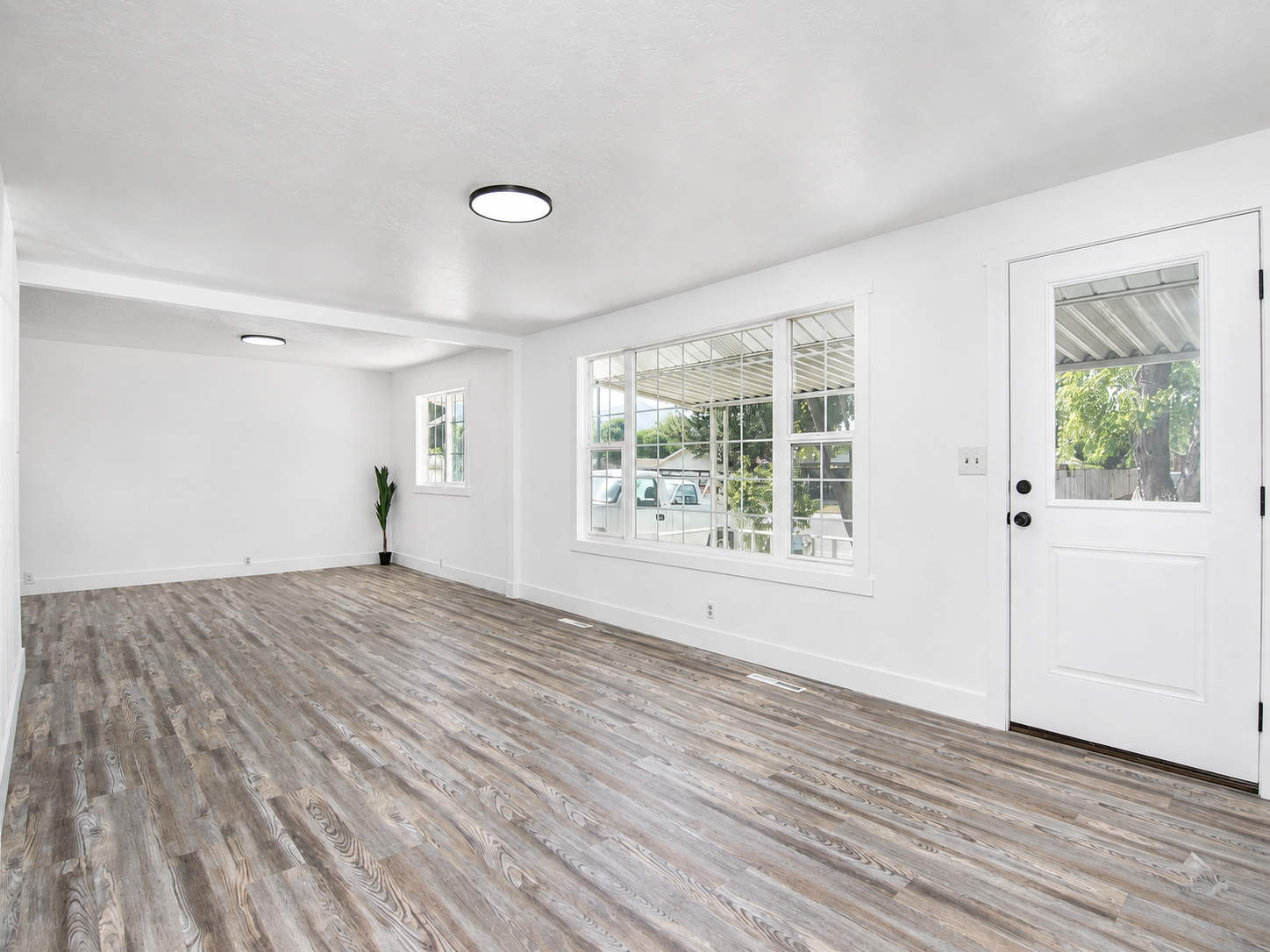 Bright finished living space with white walls and wood-look flooring